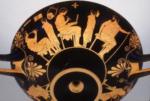 Two pairs of teachers and students. The teacher on the left, seated on an uncushioned stool, plays a flute, his mantle pushed down to his waist. His young pupil stands facing him, wrapped in his mantle. The teacher in the center is seated on a cushion.