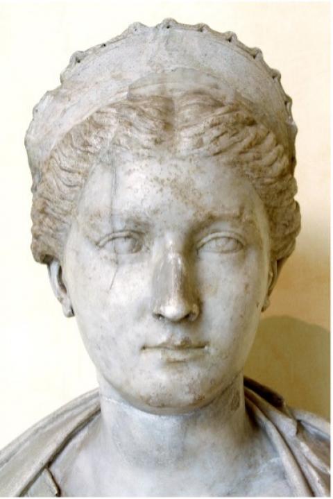 A stone sculpture of Sabina's head from the front. She has a subtle smile and wears a fillet on her hair, which is styled into an updo.